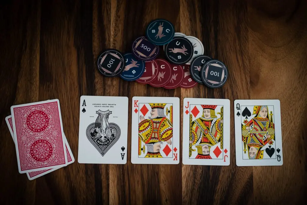 Playing cards laid out on a wooden table beside stacks of casino chips